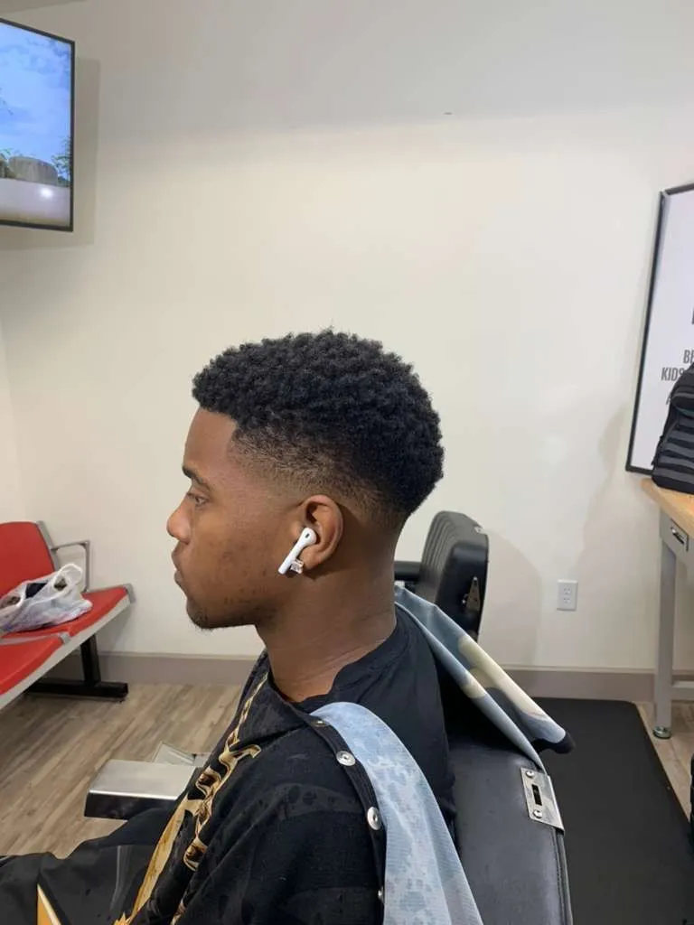 Curly afro top with a clean taper fade and razor lineup, cut at The Cave Hype in North Phoenix