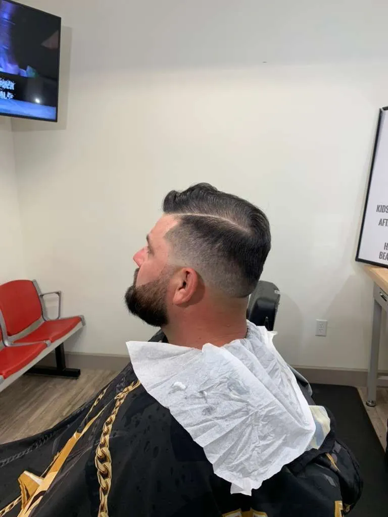 Side part comb-over over a skin fade with a shaped beard, cut at The Cave Hype in North Phoenix